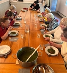 Skupina členů pojídá u stolu polévku Skupina členů pojídá u stolu polévku