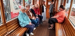 Skupina členů sedí na dřevěné sedačce v historické tramvaji Skupina členů sedí na dřevěné sedačce v historické tramvaji