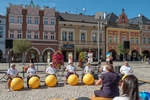 Foto z doprovodného programu - seniorky z místních domů s pečovatelskou službou sedí za velkými žlutými gymnastickými míči a bubnují na ně v rytmu hudby. Foto z doprovodného programu - seniorky z místních domů s pečovatelskou službou sedí za velkými žlutými gymnastickými míči a bubnují na ně v rytmu hudby.