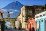 GUATEMALA - ulice lemovaná domy, v pozadí sopka