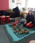 Na obrázku lektorka - sedí na zemi, před sebou má tibetské mísy a další nástroje a připravuje se k zahájení závěrečné meditace. Na obrázku lektorka - sedí na zemi, před sebou má tibetské mísy a další nástroje a připravuje se k zahájení závěrečné meditace.
