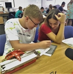 žáci si zkoušejí psaní braille pomocí tabulky