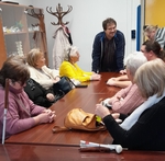 Skupina členů sedí kolem stolu na přednášce