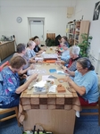 Celá skupina v akci – dlouhý stůl plný účastníků, kteří pilně pracují na svých výrobcích.