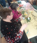 Dvě účastnice vyfocené při práci, sedí u stolu a dělají si velikonoční věnec.