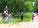Jsme zády k fotoaparátu, stojíme na sluníčku na křižovatce turistických cest a zkoumáme rozcestník.