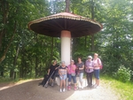 Sedíme pod obrovskou muchomůrkou. Lavice na sezení je kolem nohy celé muchomůrky.