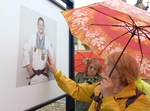 Před jednou hmatovou fotografií, na které je náš judista Lukáš Krpálek, stojí pod deštníkem žena a hmatem si prohlíží obrázek.
