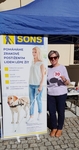 Členka SONS pózuje ve stánku s kompenzačními pomůckami Členka SONS pózuje ve stánku s kompenzačními pomůckami