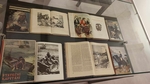 Na fotografii jsou otevřené knihy v prosklené vitríně s ilustracemi Zdeňka Buriana
